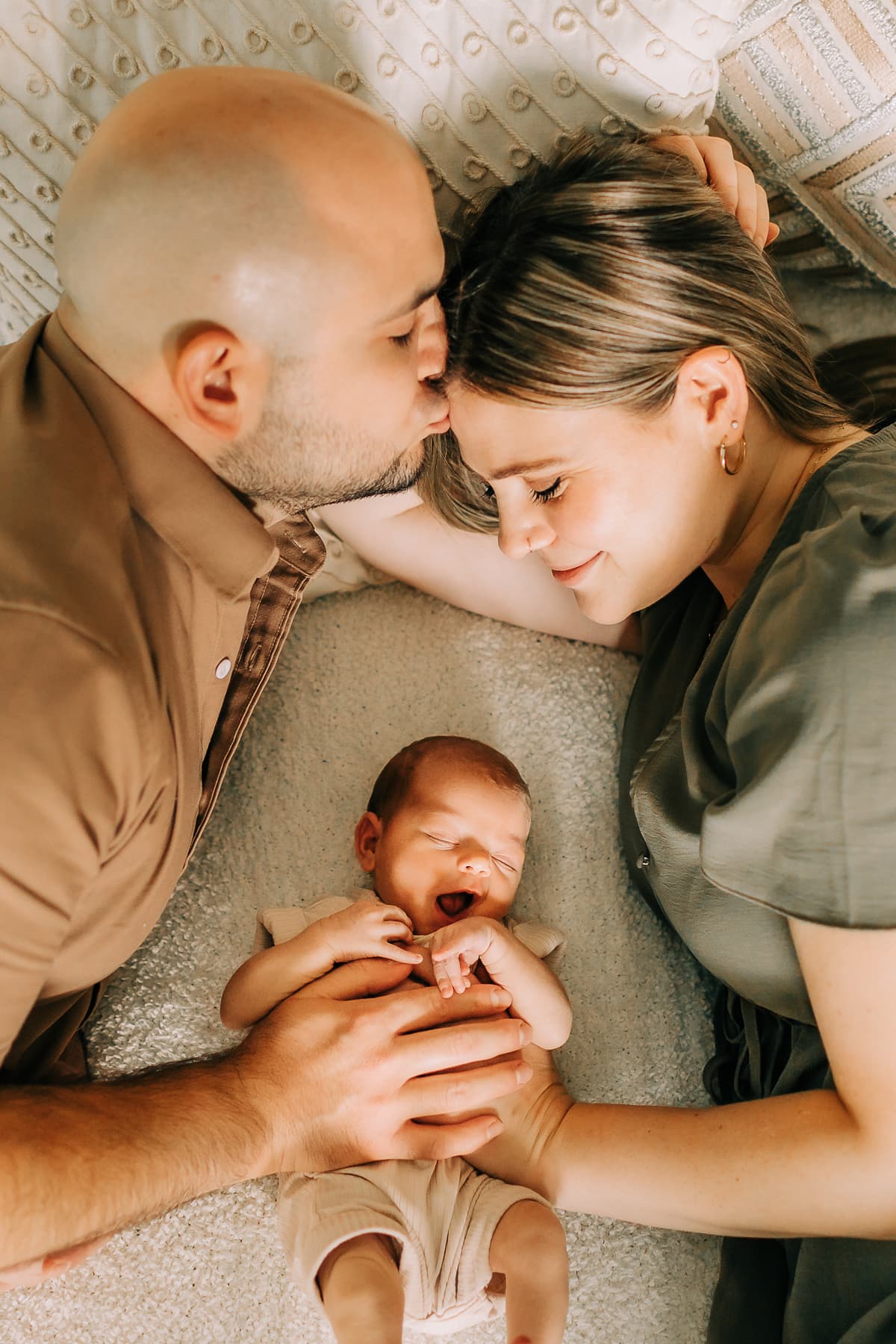 Newborn Photographer, a young mother and father hold their baby
